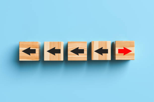 istock Wooden blocks with arrows with one stand out from the crowd and move forward on blue background. 1391405009