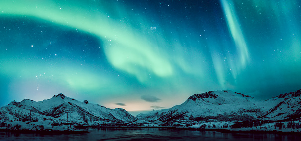 Northern Lights, polar light or Aurora Borealis in the night sky over the snow covered mountains of Austvågøy in the Lofoten islands archipelag in Northern Norway during a cold winter night.