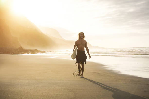 istock Young surfer man holding surf board on the beach at sunset - Focus on face 1391406549