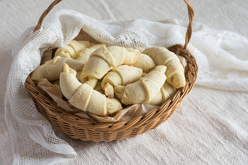 Russian homemade pastry rogaliki croissants in the rustic basket on light background. Selective focus
