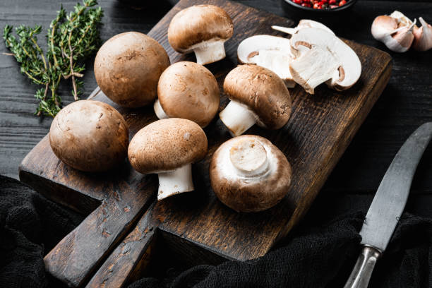 istock Brown champignons mushroom, on black wooden table background 1391409881