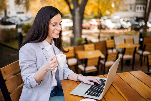 istock Young Caucasian woman sitting working on a laptop drinking coffee 1391413149