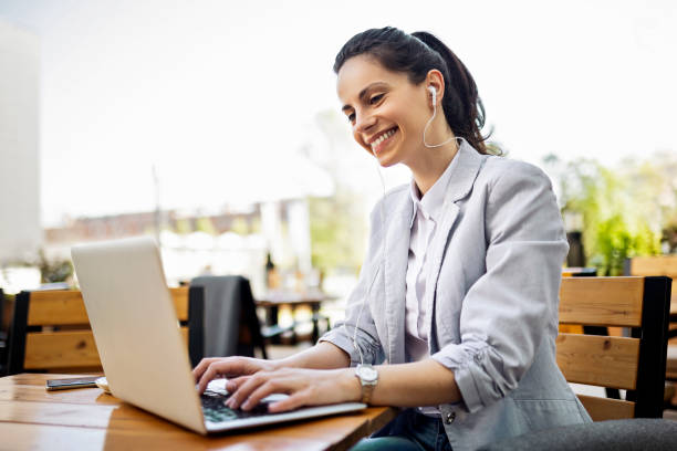 istock Young woman in a coffee working on a laptop using headphones 1391413166