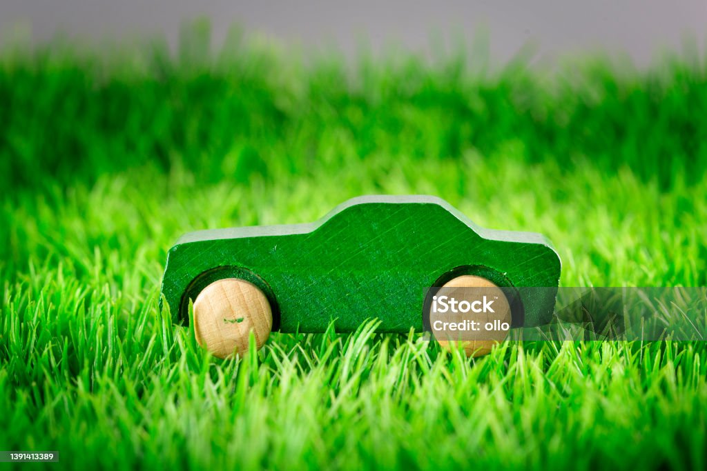 Wooden toy car on green grass - concept of sustainable mobility Greenwashing Stock Photo