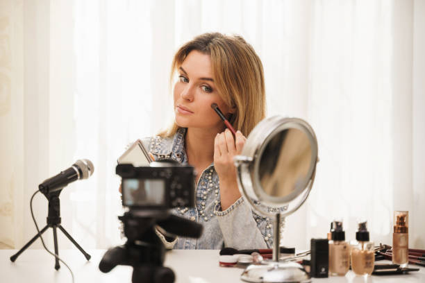 istock Woman beauty blogger applying blush on her face during video tutorial recording for her followers 1391416097