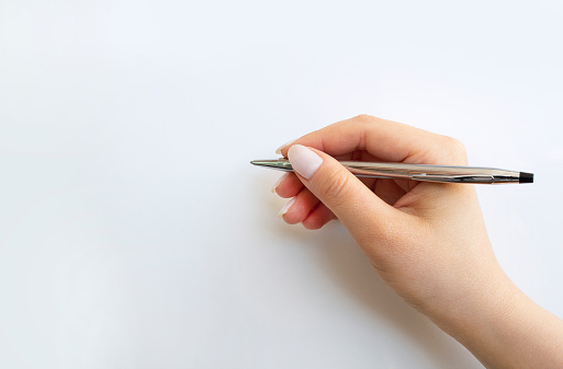 Close-up Female hand writing with a pen, pen in hand, isolated on white background.