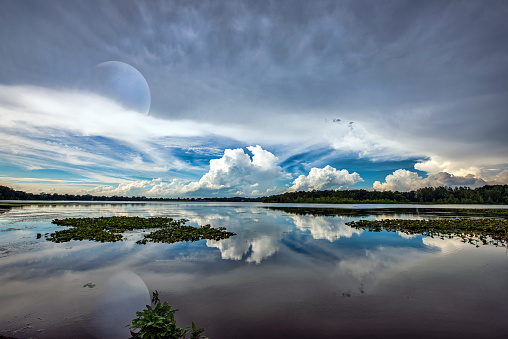 Planet in the sky over calm lake with clouds.