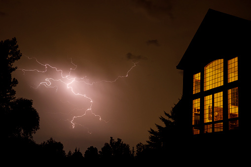 Crackling lightning near the window of a residential home in the Midwest