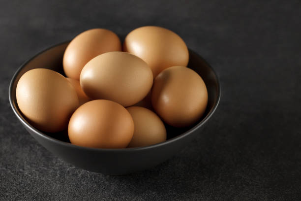 istock Eggs chicken, whole, in bowl on dark background, selective focus. 1391429352
