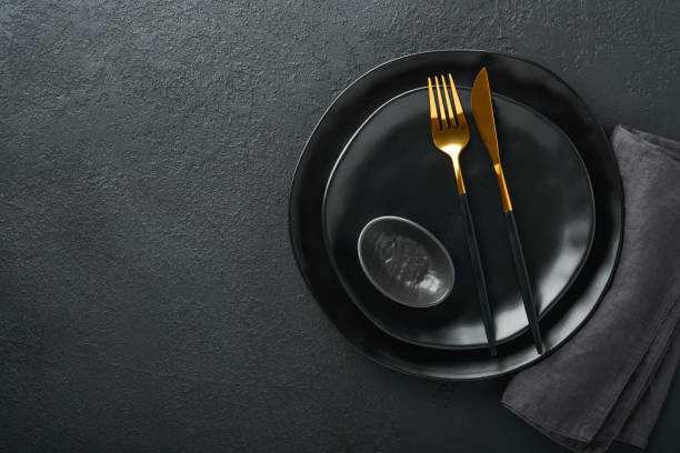 istock Ceramic empty black plate, silverware and linen kitchen towel napkin on old black ceramic cement concrete table background. Cooking stone backdrop. Top view with copy space. Flat lay 1391434844