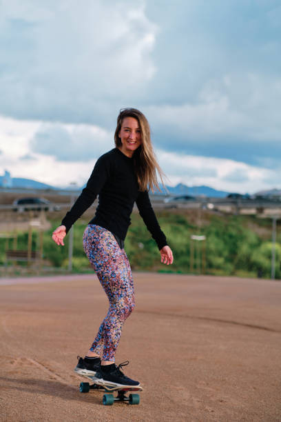 istock Young blonde woman practicing skateboarding in public park 1391439448