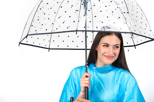 Portrait of a beautiful woman standing next to a park bench under an umbrella on a rainy day