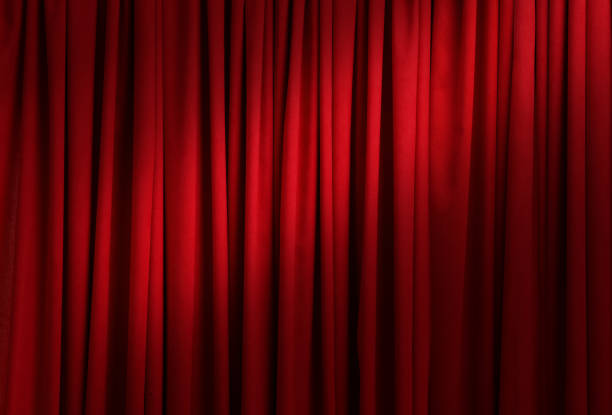 istock Spotlight illuminating closed red stage curtains. Start of performance 1391445995