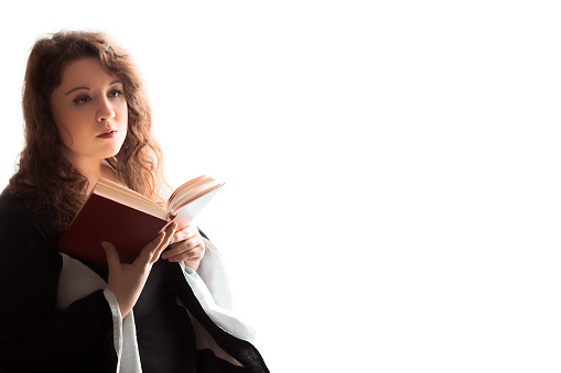 Young woman portrait holding old book and looking away, lost in her thoughts