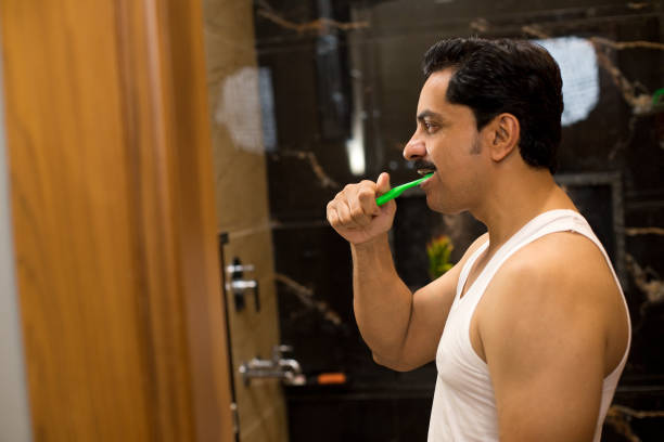 Profile of man brushing his teeth in the bathroom at home