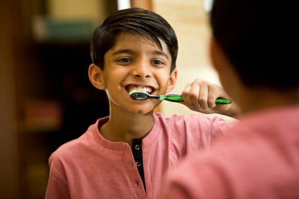 Boy brushing his teeth in bathroom stock photo