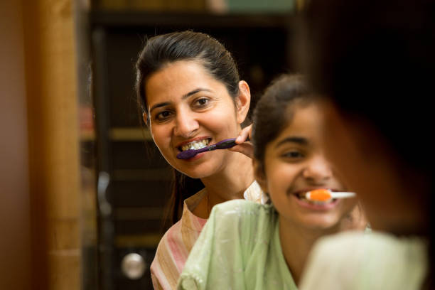 mère et fille se brossent les dents ensemble à la salle de bain - hygiene dental hygiene human teeth child photos et images de collection