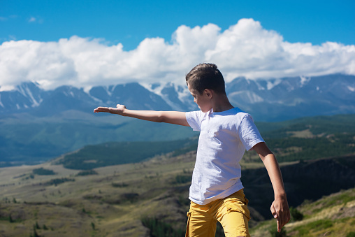 A child funny boy on the Altai mountain background. Concept of tourism, travel, lesure and freedom. Altai mountain, beauty summer evening landcape