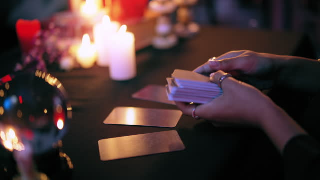 Psychic laying out tarot cards on table to read client's past and predict future