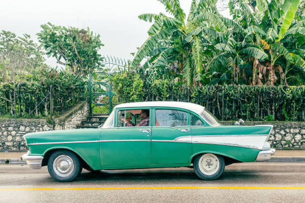 Santa Clara, Villa Clara, Cuba - November 7, 2019: A Cuban man drives an old Chevrolet 1957.  The scene is taken on a rainy and overcast weather in the Central Road which is one of the main streets in the provincial capital city.