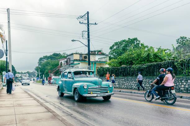 Santa Clara, Cuba - November 7, 2019: Cuban people are seen in the Central Road where an old American car works as a taxi. Morning scene on a rainy day.