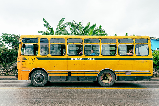 Santa Clara, Cuba - November 7, 2019: A yellow Giron bus drives in the Central Road carrying few passengers. The vehicle reads 'School Transport' on its side.