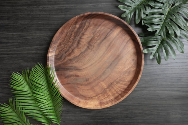 istock Round teak tray and green leaves 1391453696