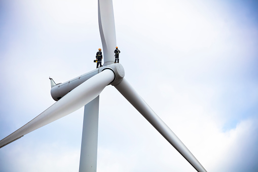 maintenance technician working on huge wind turbine,renewable and green energy concept