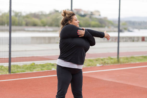 istock Obese Hispanic stretching her arm before outdoor weight loss training 1391456935