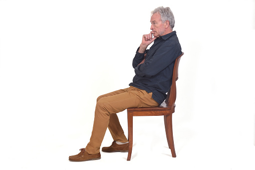 side view of a pensive man sitting on a chair on white background