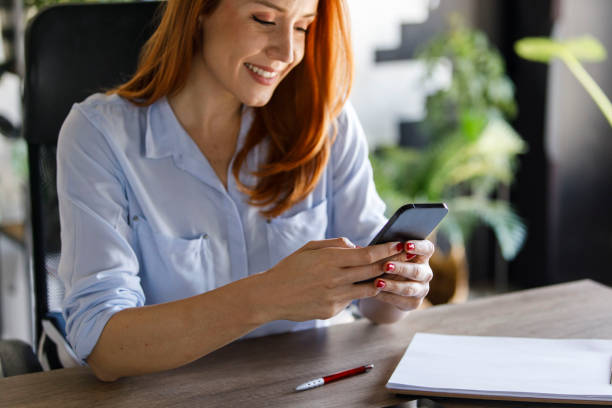 istock Young businesswoman responding to a text message on her smart phone while working 1391463810