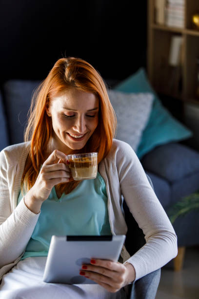 istock Happy young woman enjoying coffee and using digital tablet while relaxing 1391465465