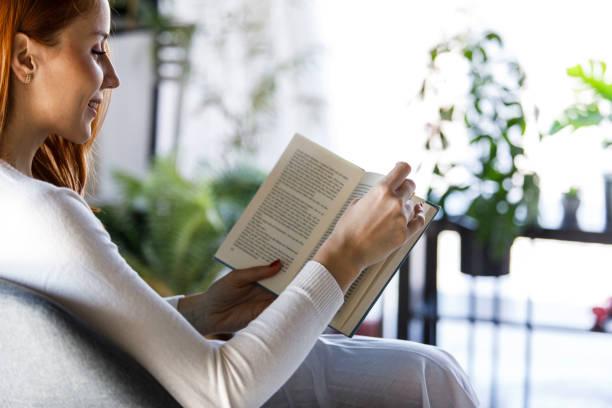 istock Copy space shot of smiling redhead reading an interesting book while relaxing 1391465584