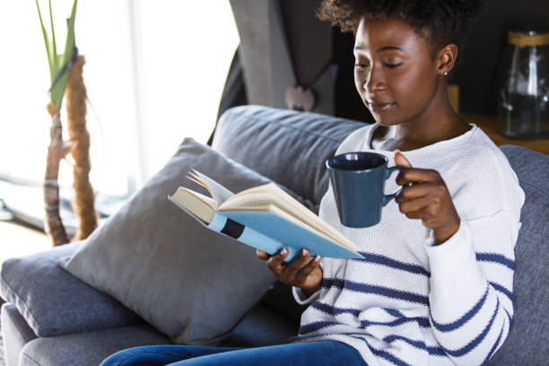 istock Joyful young woman reading a book while enjoying morning coffee 1391467869