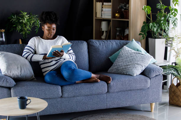 istock Young woman relaxing on the sofa after work and enjoying reading a book 1391467871