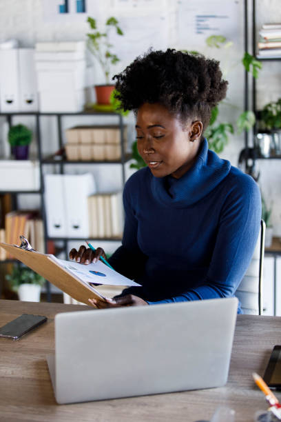 istock Young businesswoman analyzing documents on a clipboard she is holding 1391468427