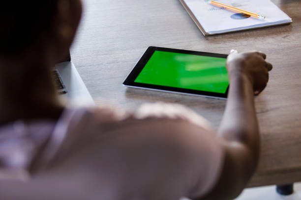 istock Woman reaching for a digital tablet with chroma key on the screen 1391469404