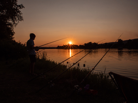 A fisherman watches the sunset as he's fishing