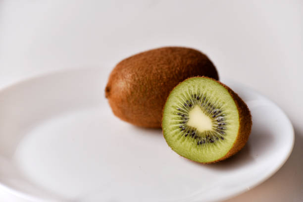 istock A whole kiwi fruit and half on a white plate 1391471990