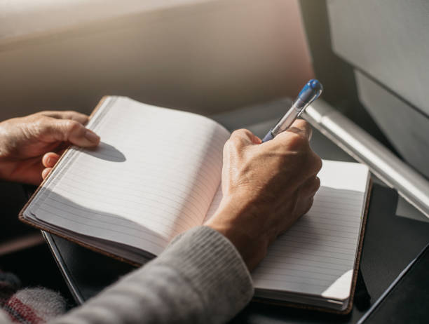 istock a person writes in a diary on a train while traveling. the soft light comes in through the window. work and travel concept. 1391474301