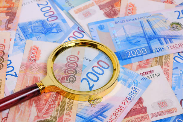 istock Magnifying magnifier against background Russian rubles denominations five and two thousand. 1391476548