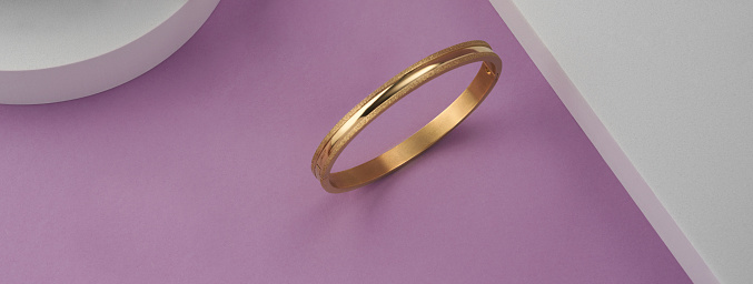 Panorama of modern golden bracelet on pink and white background