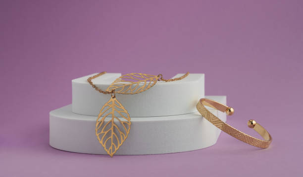 Leaf shape Necklace pendant and geometric pattern bracelet on white podium on purple background with copy space
