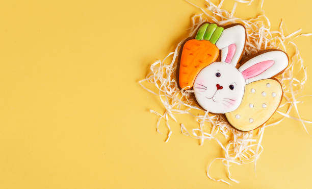 istock Gingerbread cookie in the shape of rabbit head with carrot and egg. Easter bunny cookie on the yellow background. 1391480508