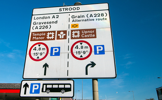 Road Sign to Strood at Rochester in Kent, England, with a tyre shop and people visible in the distance