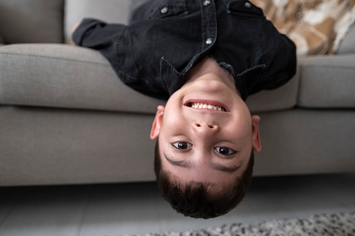 Little boy upside down on sofa at home playful child at home playing