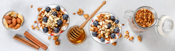 granola parfait mit griechischem joghurt, hafermüsli, frischen beeren, honig und minzblättern im hohen glasgefäß. gesundes frühstückskonzept. bio-hafer-, mandel- und sonnenblumenkerne. draufsicht, menügestaltung, kopierraum - jar oatmeal granola glass stock-fotos und bilder