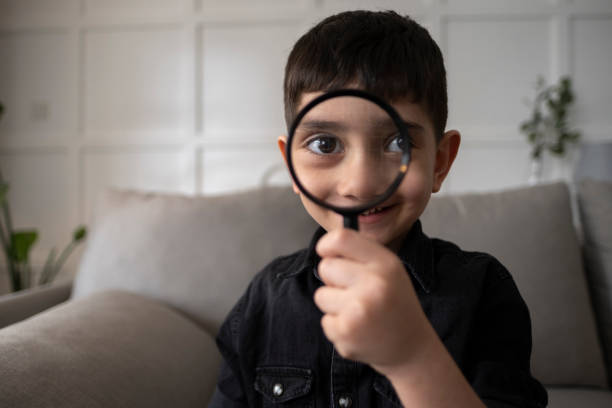 istock Portrait Of Cute Boy Using Magnifying Glass 1391484261