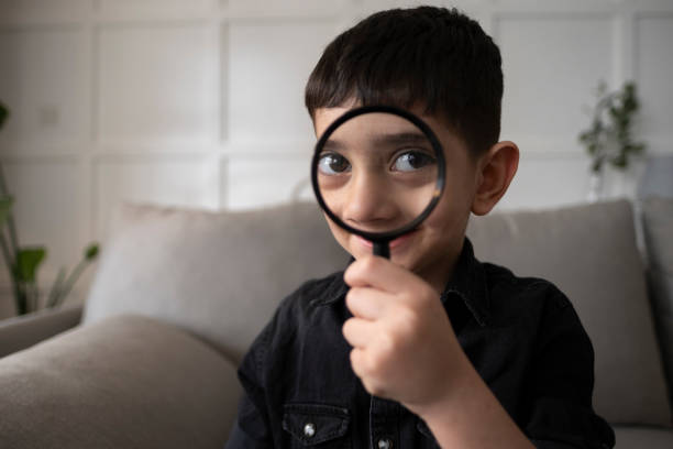istock Portrait Of Cute Boy Using Magnifying Glass 1391486205