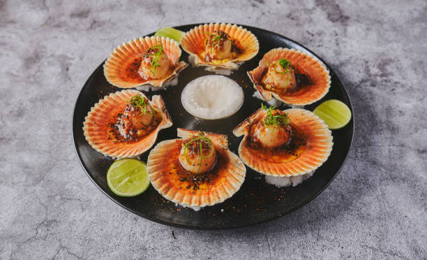 istock Scallops with flamed shells on a black plate. Luxury restaurant food. Seafood, selective focus. 1391487698